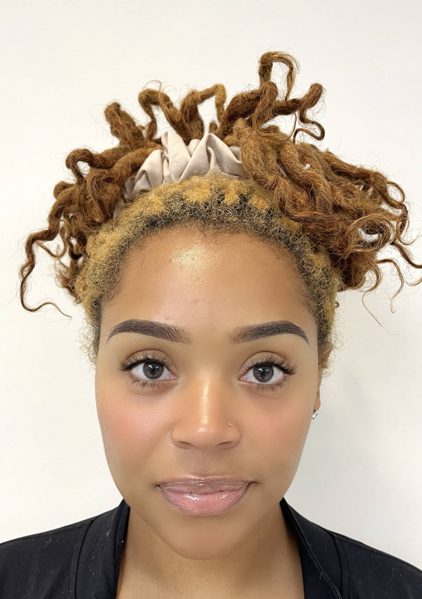 A client with locs tied up, facing the camera, photographed at the end of the appointment with fresh dark brows.