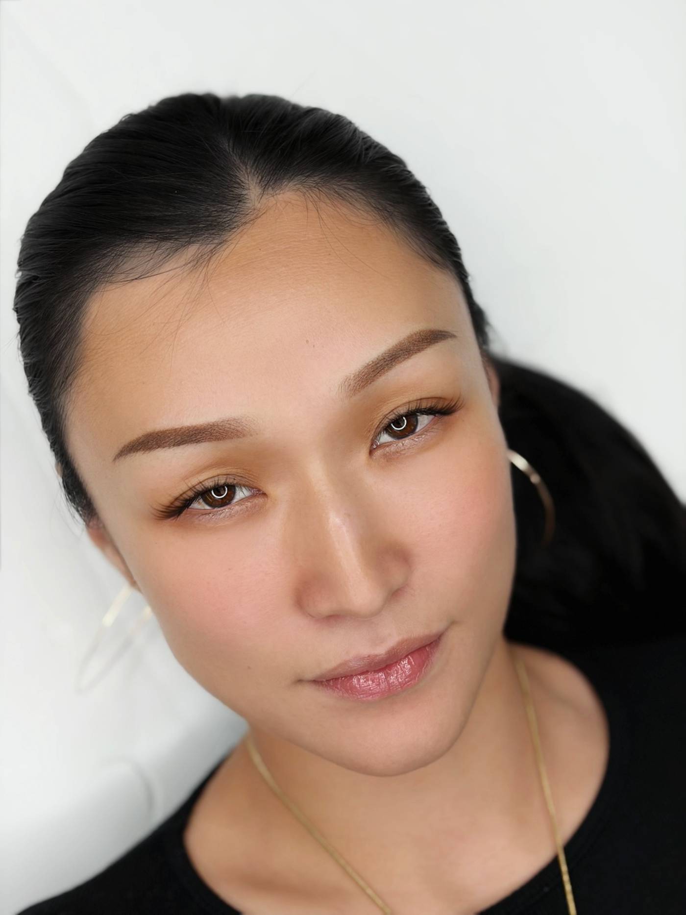A client with dark hair pulled back, photographed close at the end of the appointment, with fresh soft brown brows.